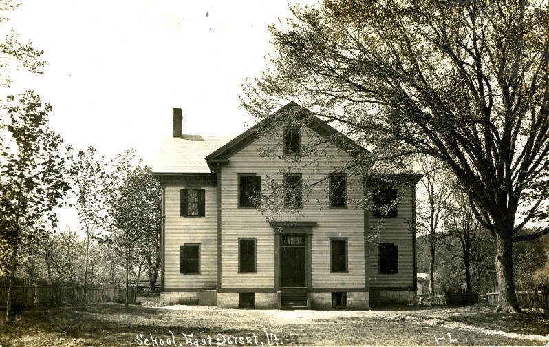 A two-story schoolhouse on a stone foundation, on an old postcard.