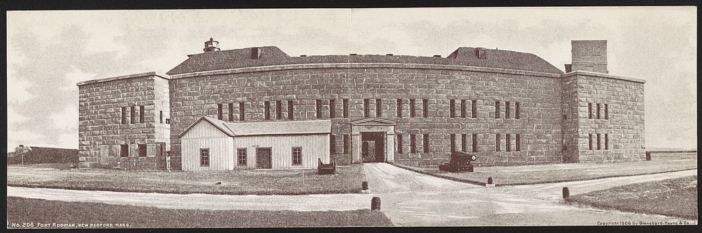 Postcard of Fort Rodman, a granite fort with a cannon at its entrance and a lighthouse above the roofline.