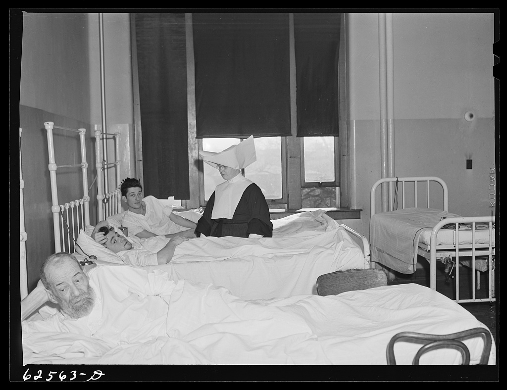 A black-and-white photograph of a hospital charity ward with rows of beds.