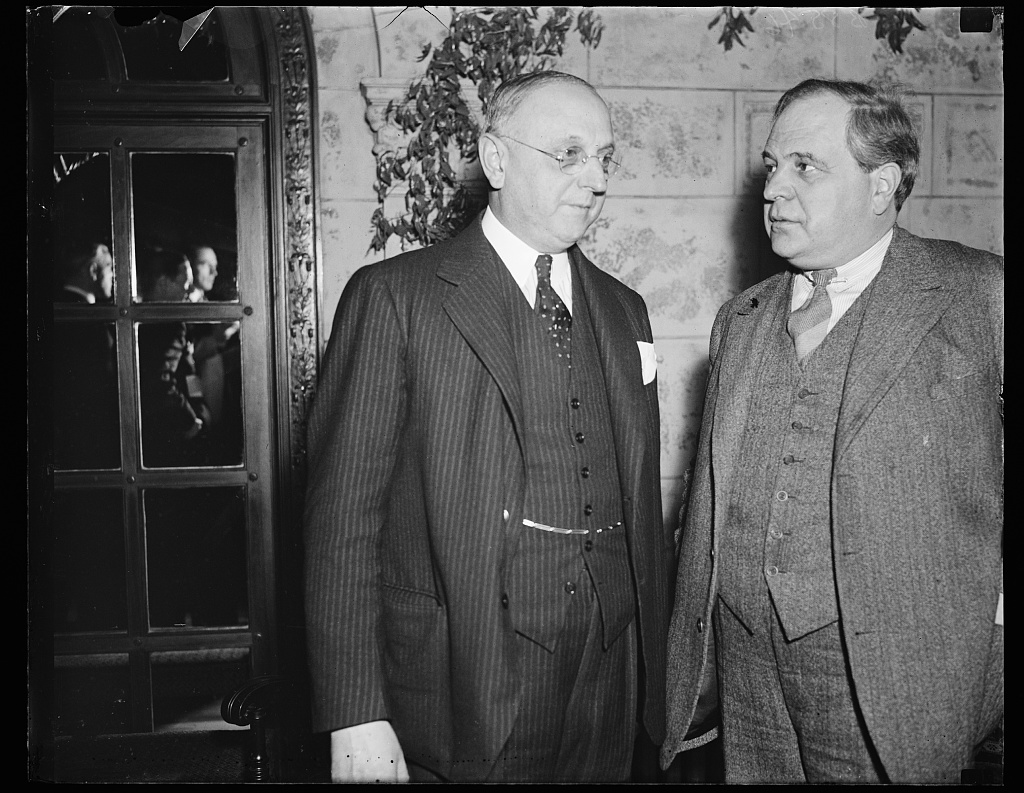 A press photograph of several men in suits standing together; Frank Buchman is at the left.