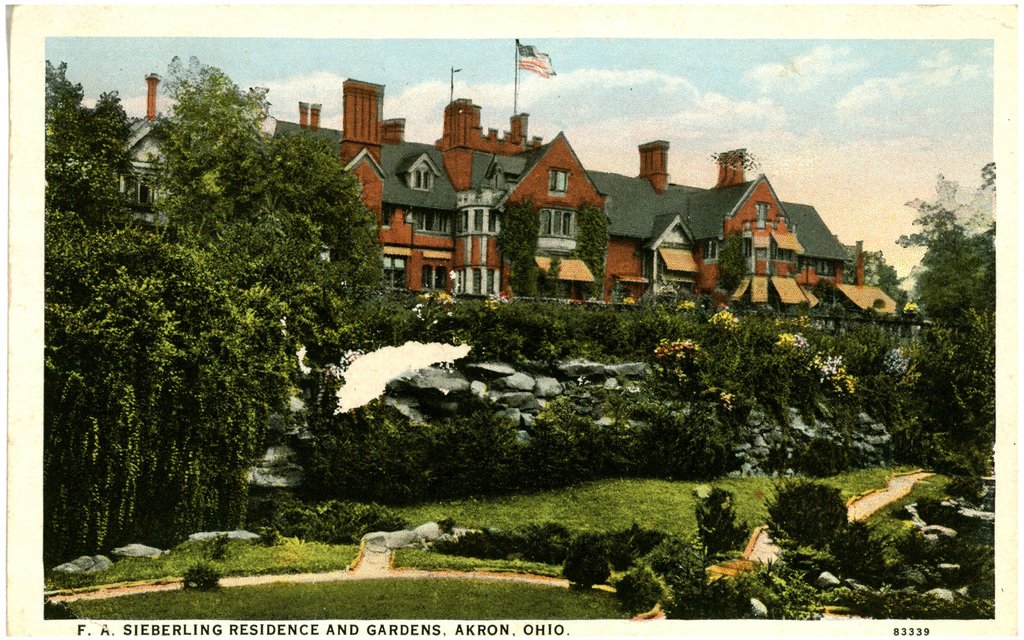 A color postcard of a large Tudor-style mansion with formal gardens.