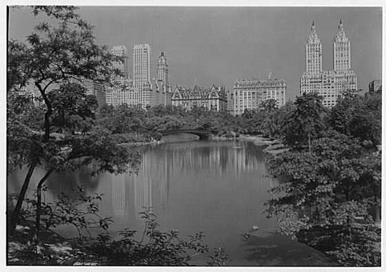 The apartment buildings of Central Park West reflected in a lake in Central Park, 1932.